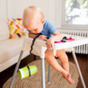 Baby in highchair dropping cup attached to Busy Baby Bottle Bungee