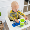 Baby at highchair with Busy Baby Mini Mat silicone mat and Busy Baby Bottle Bungee