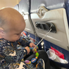Baby playing with toy attached to Tether attached to Busy Baby Mini Mat silicone mat on airplane tray table