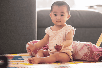 baby sitting holding strawberry