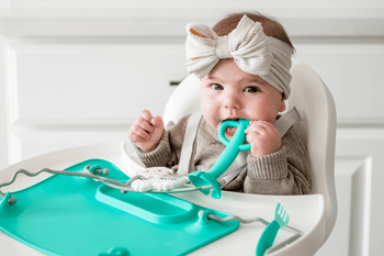 baby using 2-in-1 teether&training spoon in highchair