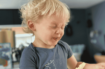 baby making a sour face while eating