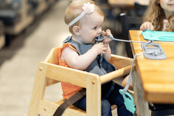 baby holding 2-in-1 teether&training spoon eating from busy baby silicone mini mat