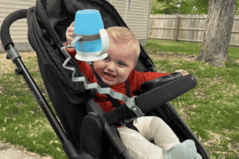 baby in stroller throwing cup attached with busy baby bottle bungee