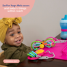 A baby sitting at a table with Toys attached to the Busy Baby Original Mat