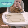 Child in a high chair with a tan busy baby mat attached, featuring text about suction security.