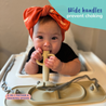 Baby using a 2-in-1 teether and training spoon with text about wide handles preventing choking.