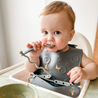 Baby eating off of spoon connected to Pewter Busy Baby Stop Drop Travel Bib+Utensils
