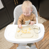 Baby eating off the tan busy baby silicone placemat in highchair