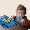 Baby eating at table with Blue Busy Baby Mat silicone mat with Busy Baby Utensils